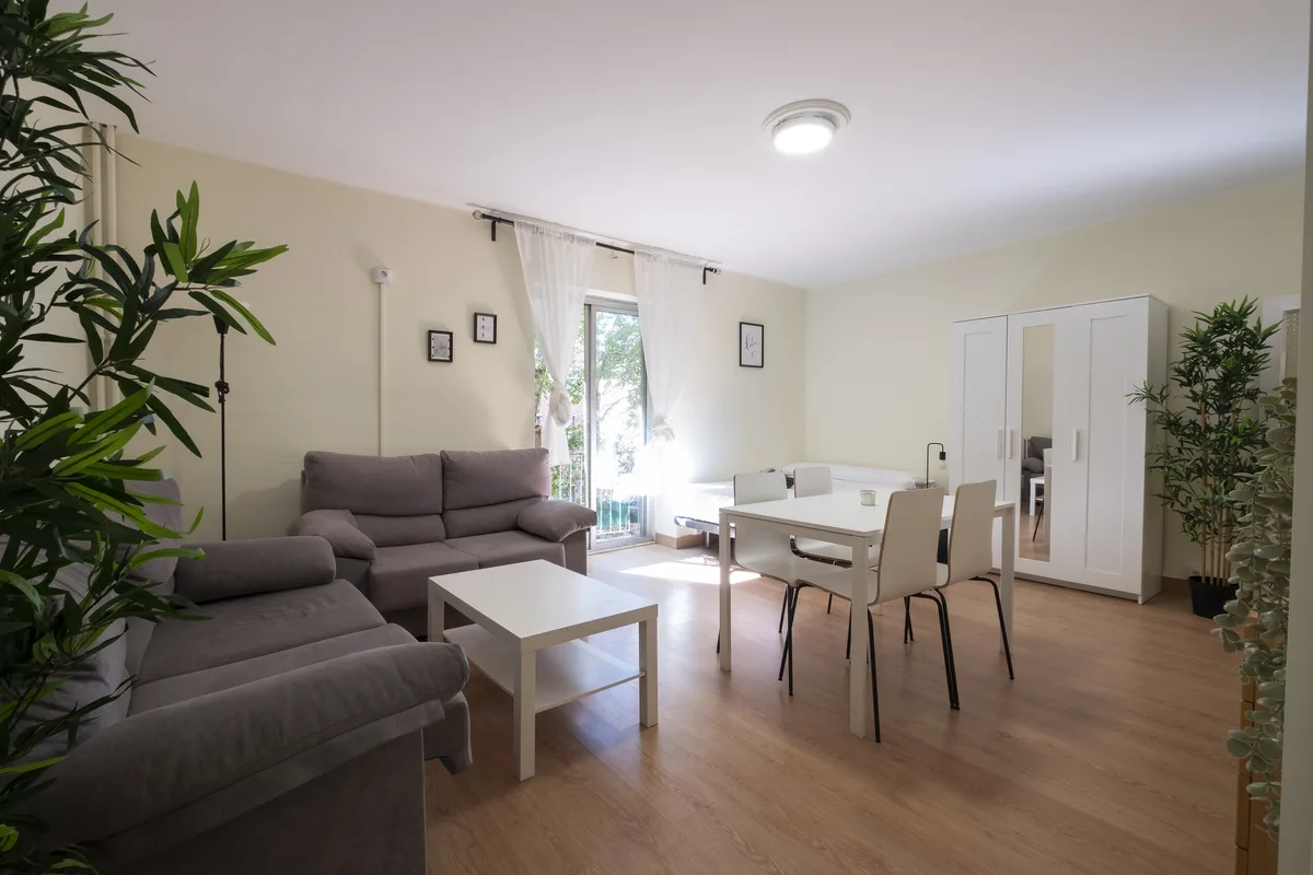 Salón reformado de una vivienda gestionada por Verantia, con sofás, mesa de comedor y balcón